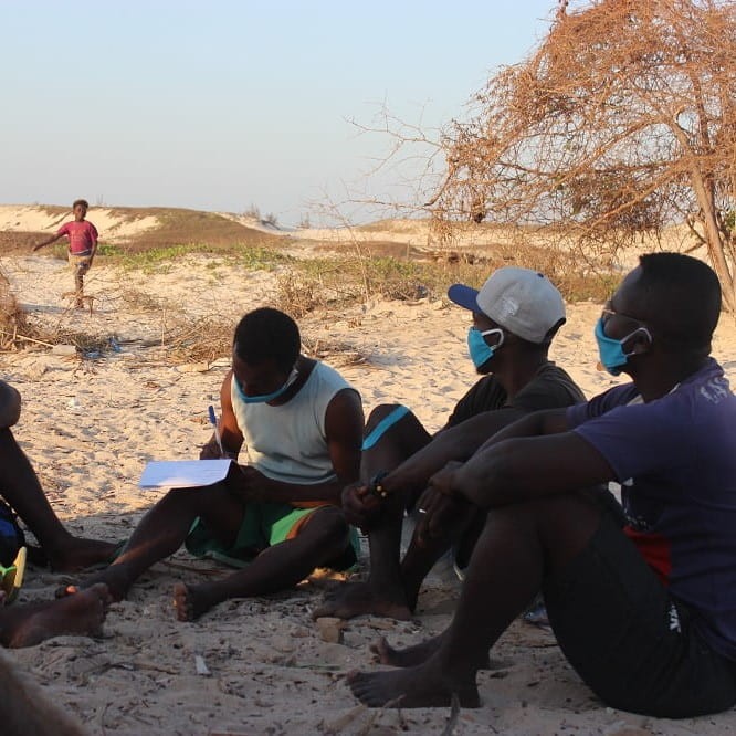 MAP Team - group of people sitting on the sand with child walking toward them