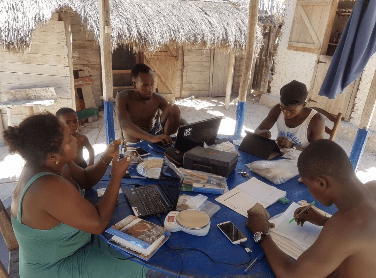 Group of people working around a table with computers and stacks of paper